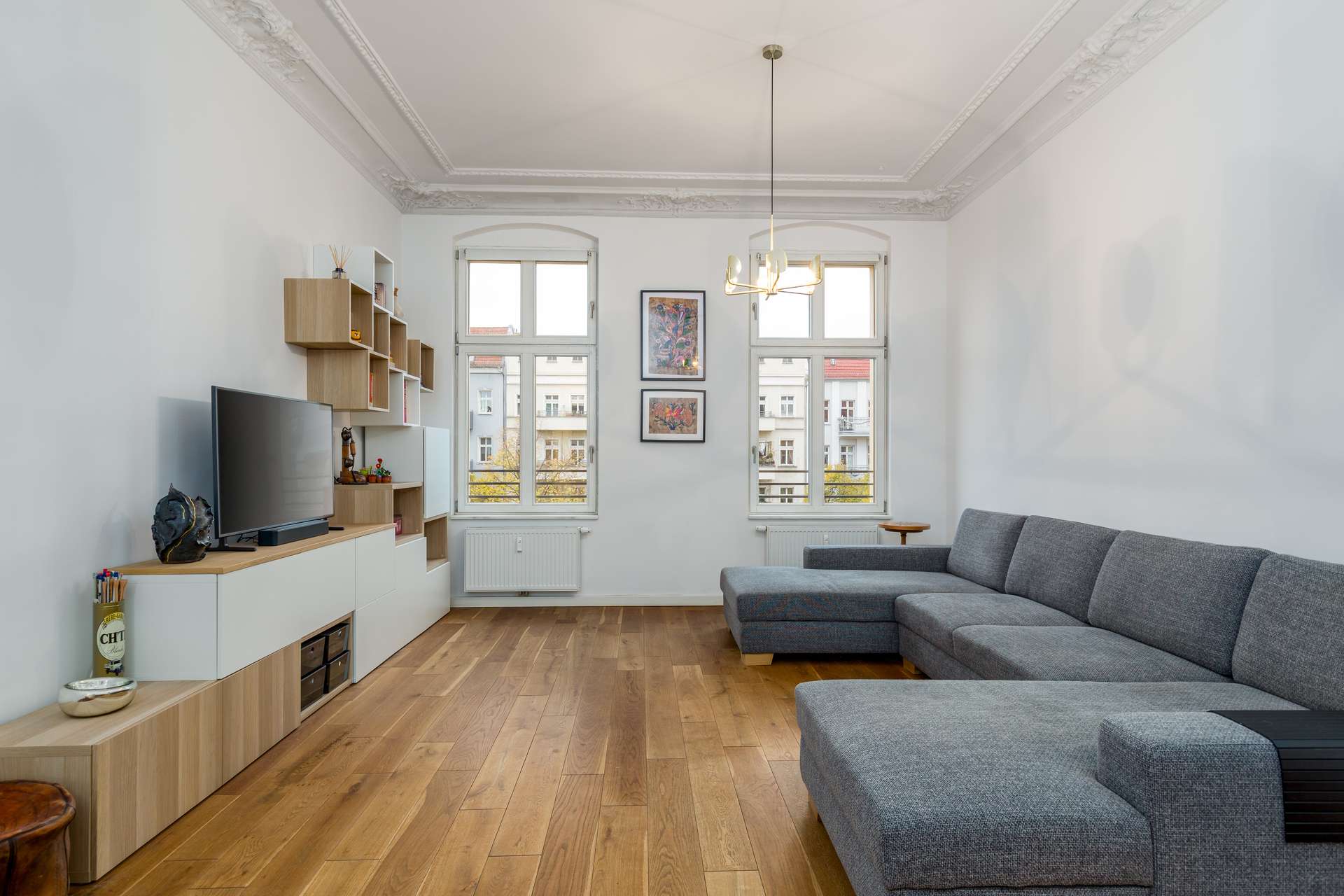 Helles Wohnzimmer mit originalem Deckenstuck, Eichenparkett und hohen Fenstern